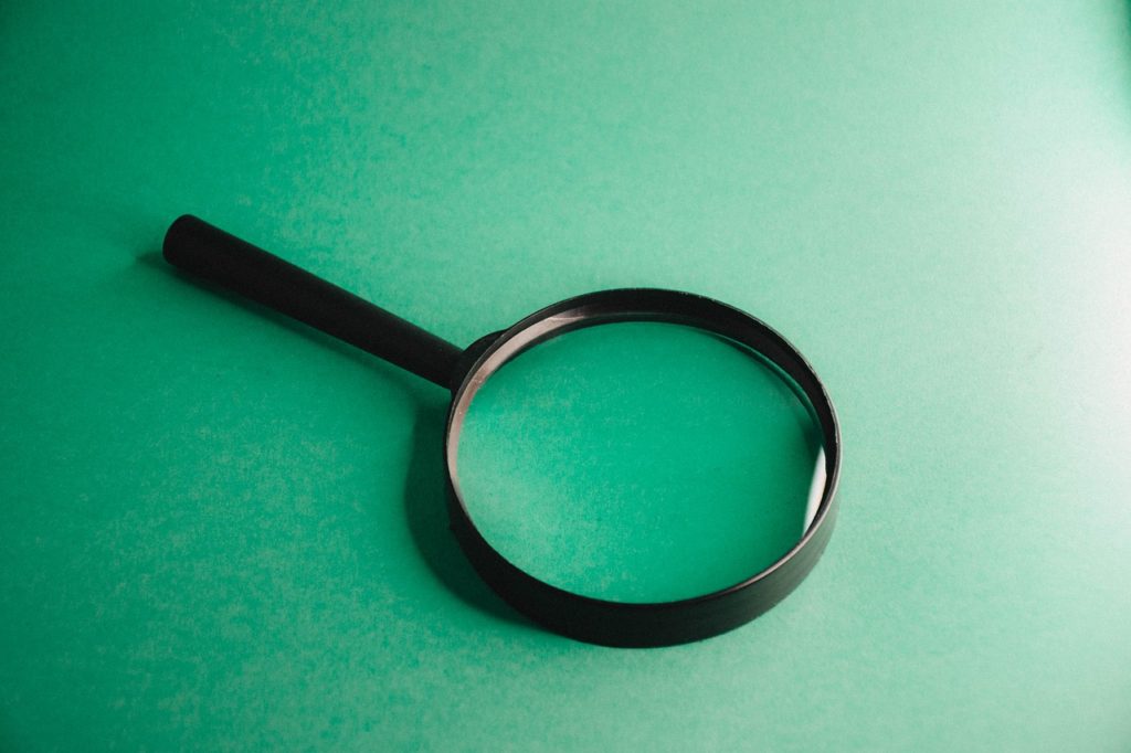 5 aspectos obrigatórios para analisar ao revisar uma Copy profissional - Lupa preta sobre um superfície verde