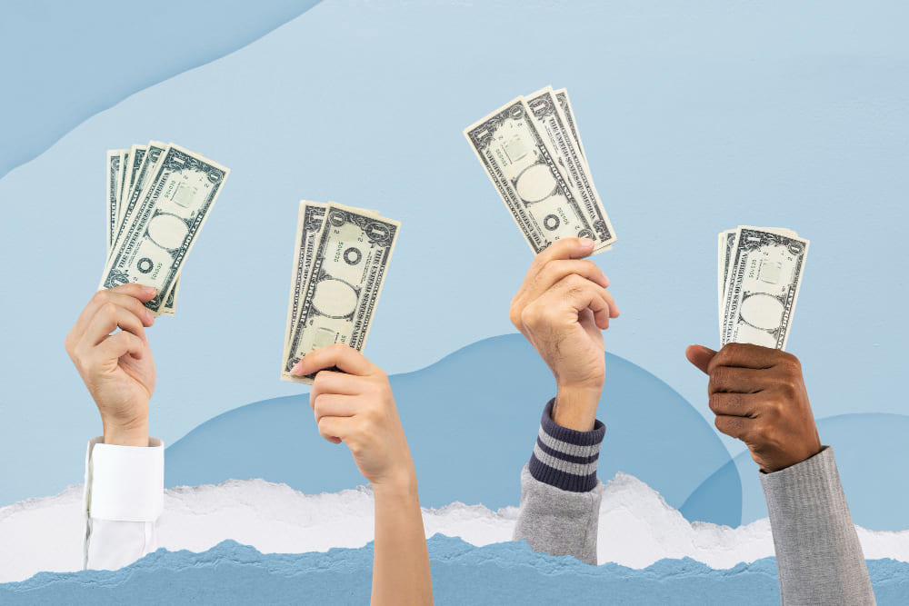 A habilidade milionária ignorada na Profissão Social Media - Quatro mãos segurando notas de dólares sobre um fundo azul.