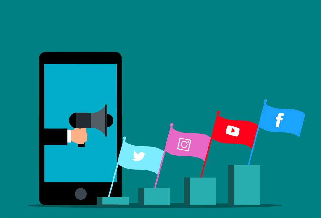 7 tipos de anúncios mais utilizados no Marketing Digital - Ilustração de uma mão segurando um megafone dentro de um celular e 4 bandeiras representando as redes sociais Twitter, Instagram Youtube e Facebook