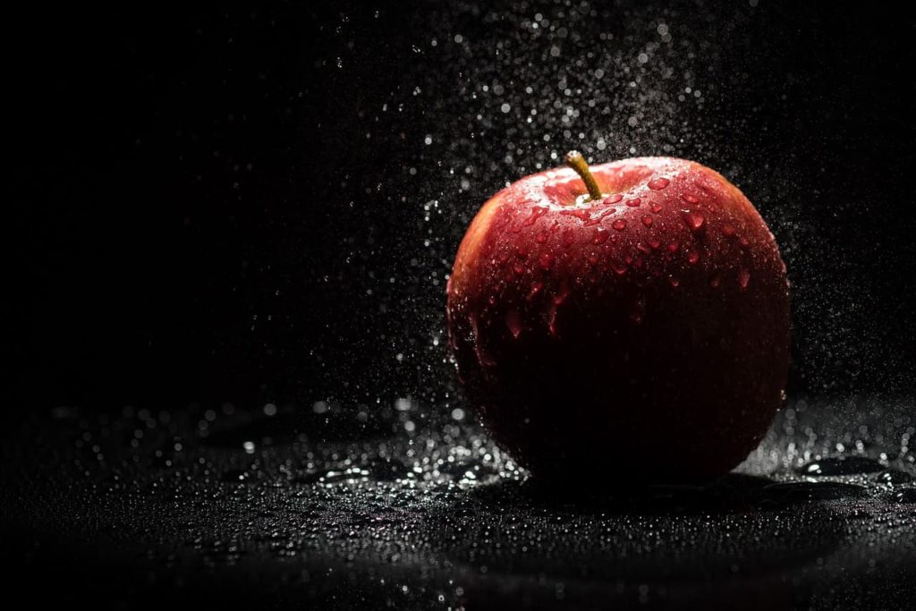 Gatilho mental da antecipação: o segredo bilionário da Apple - Imagem de uma maçã úmida sobre um fundo escuro